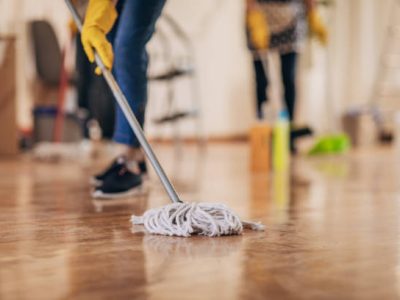 Two women, mature women cleaners from cleaning service, cleaning floor in apartment together.